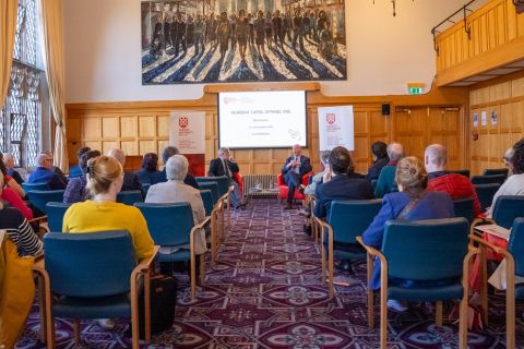 Two men sitting in chairs at the front of the room where the event was held