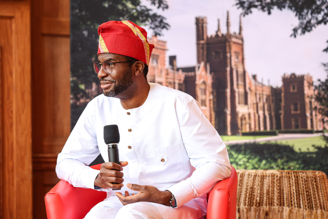 Black man with ethnic attire sitting and holding a microphone