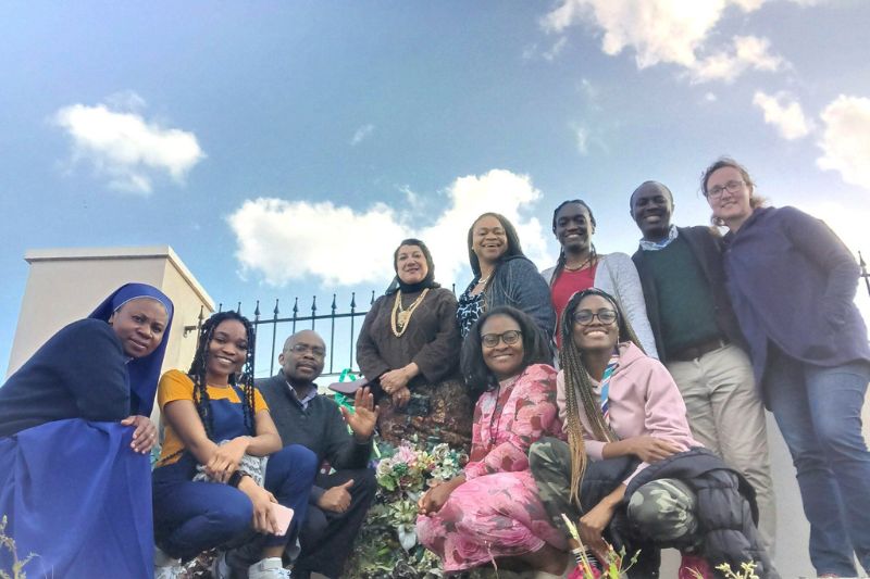 Diverse group of people, half sitting half standing in the open air