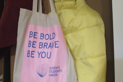 QUB SU tote bag hanging on door