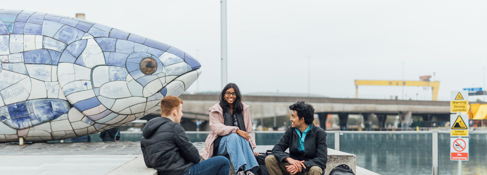 Three students sit beside Big Fish