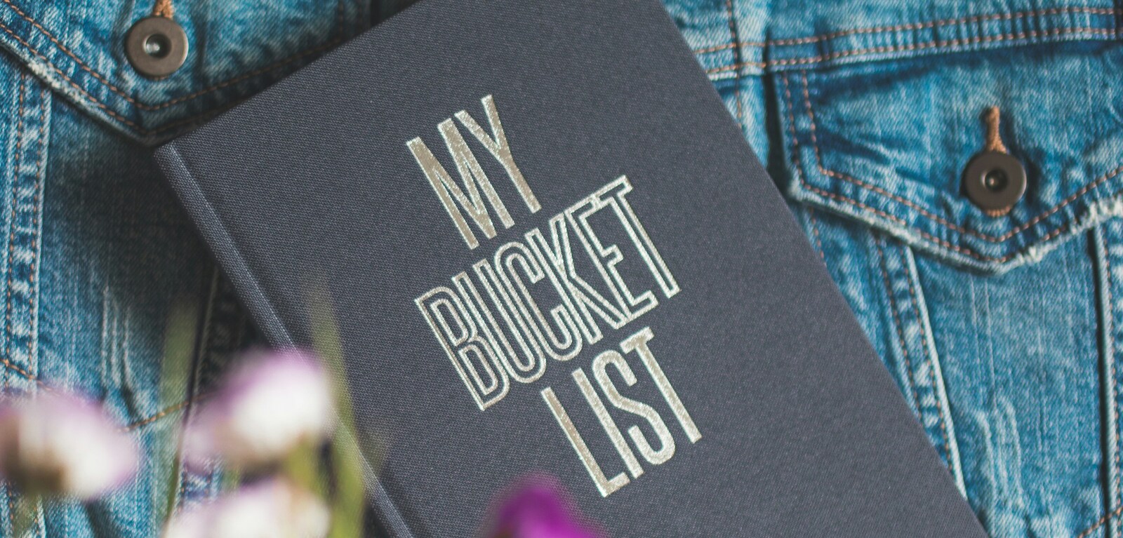 Woman holding grey book with the words 'My Bucket List' on the front cover