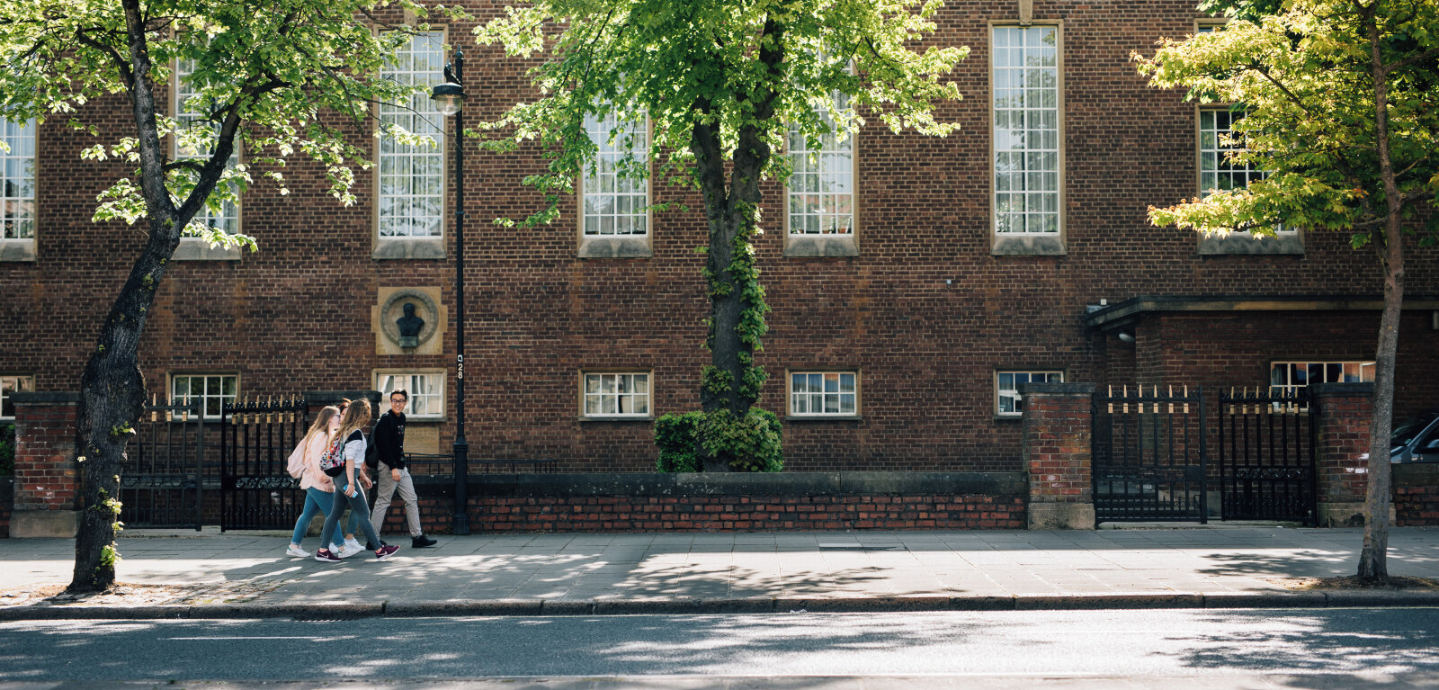 Three students walking through campus in summer