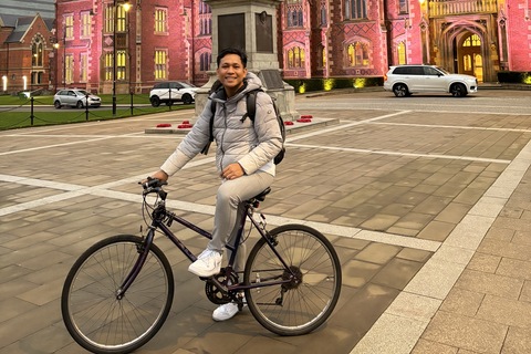 Student Muhammad on bike in front of Lanyon building