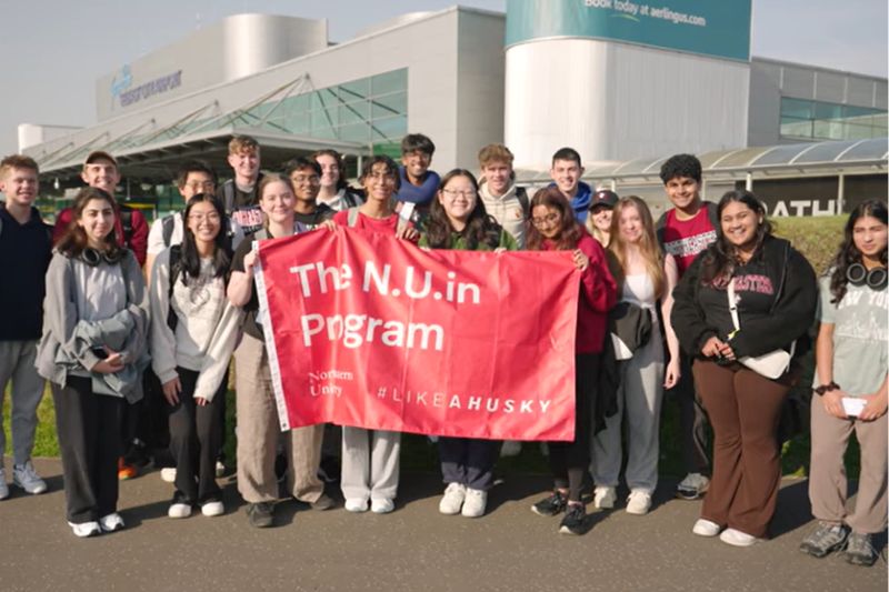 Group of students holding a Northeastern uni banner