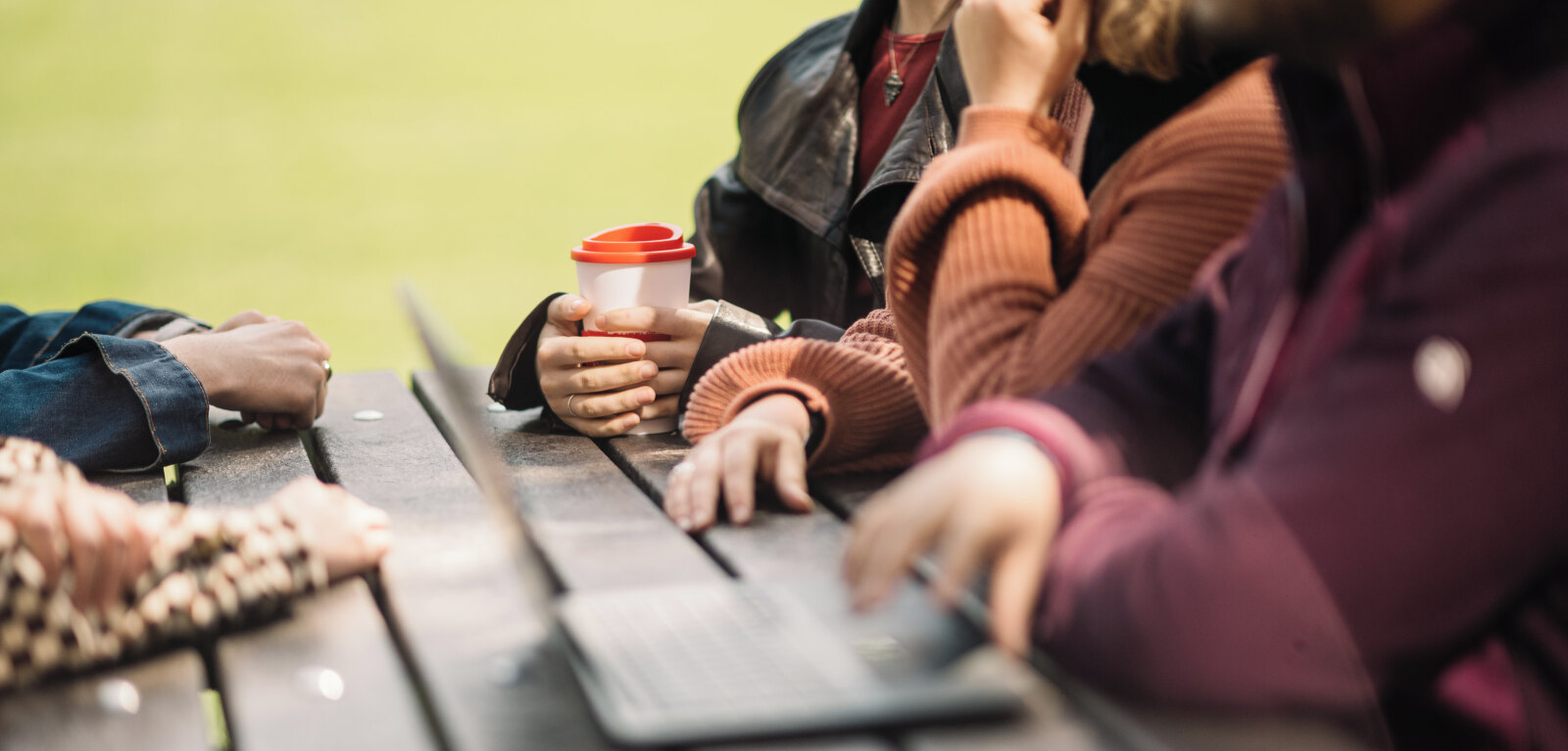 Students sitting on bench, one holding a coffee cup