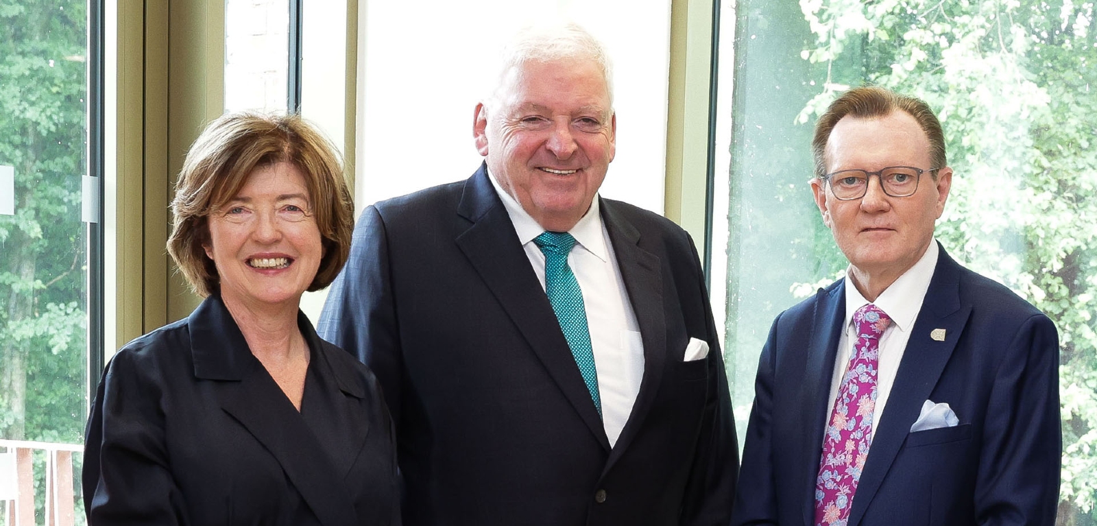 Baroness Gray, Dr McCormack, and Professor Sir Ian Greer stand side by side smiling at the camera