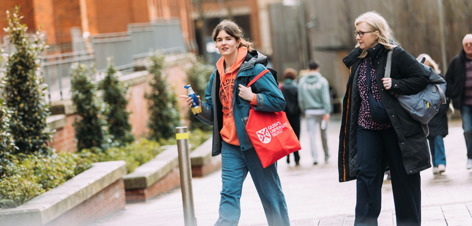 Student with QUB tote bag walking towards the Quad