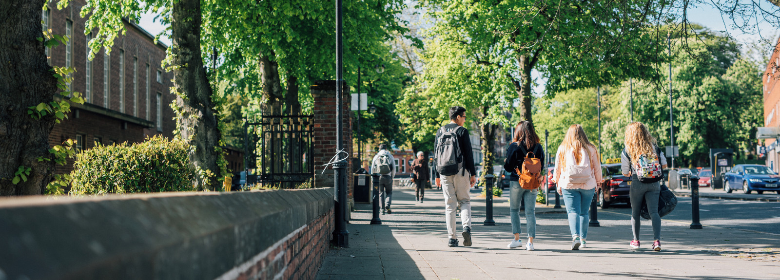 Group of four students walking past Lanyon building towards Stranmillis