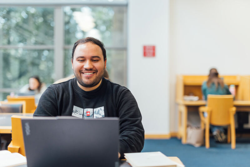 Student Miguel on laptop in library